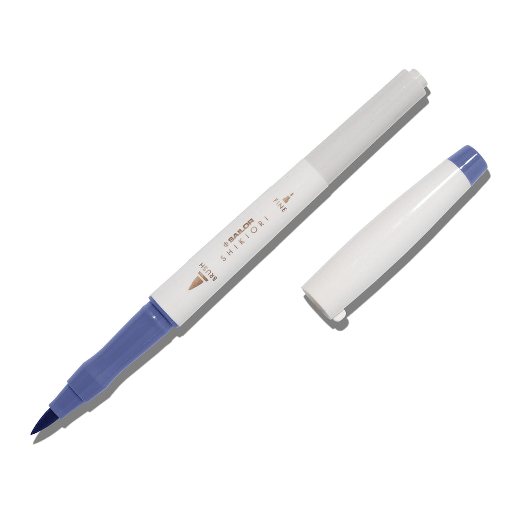 Brush pen displayed on a white background. It is uncapped with its brush nib exposed, and the cap lying parallel to the marker. Color pictured is Nioisumire. 