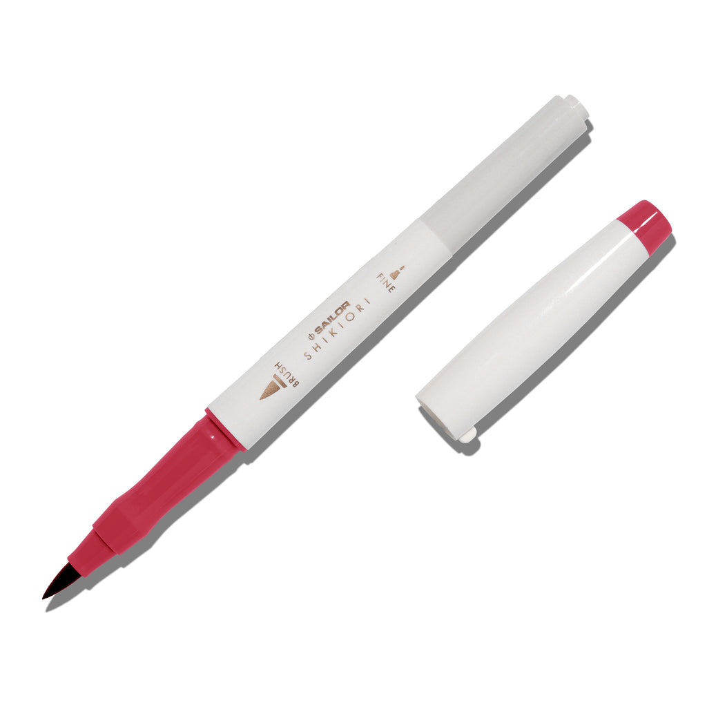 Brush pen displayed on a white background. It is uncapped with its brush nib exposed, and the cap lying parallel to the marker. Color pictured is Yodaki. 