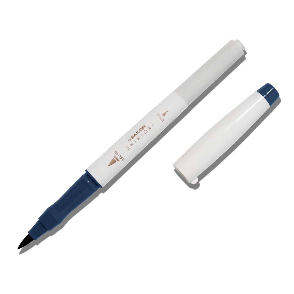 Brush pen displayed on a white background. It is uncapped with its brush nib exposed, and the cap lying parallel to the marker. Color pictured is Yonaga. 