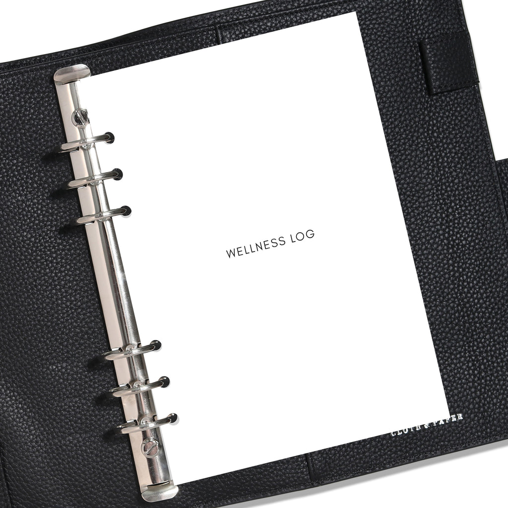 A5 Wellness Log insert displayed in a black leather planner. Title page is shown. 