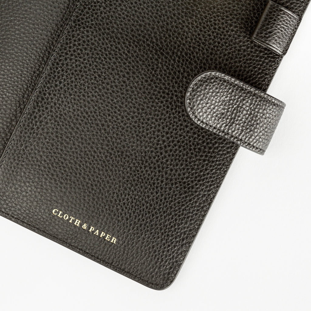 Close up of pen loop, snap closure, and Cloth and Paper logo embossed into the bottom center of the agenda.