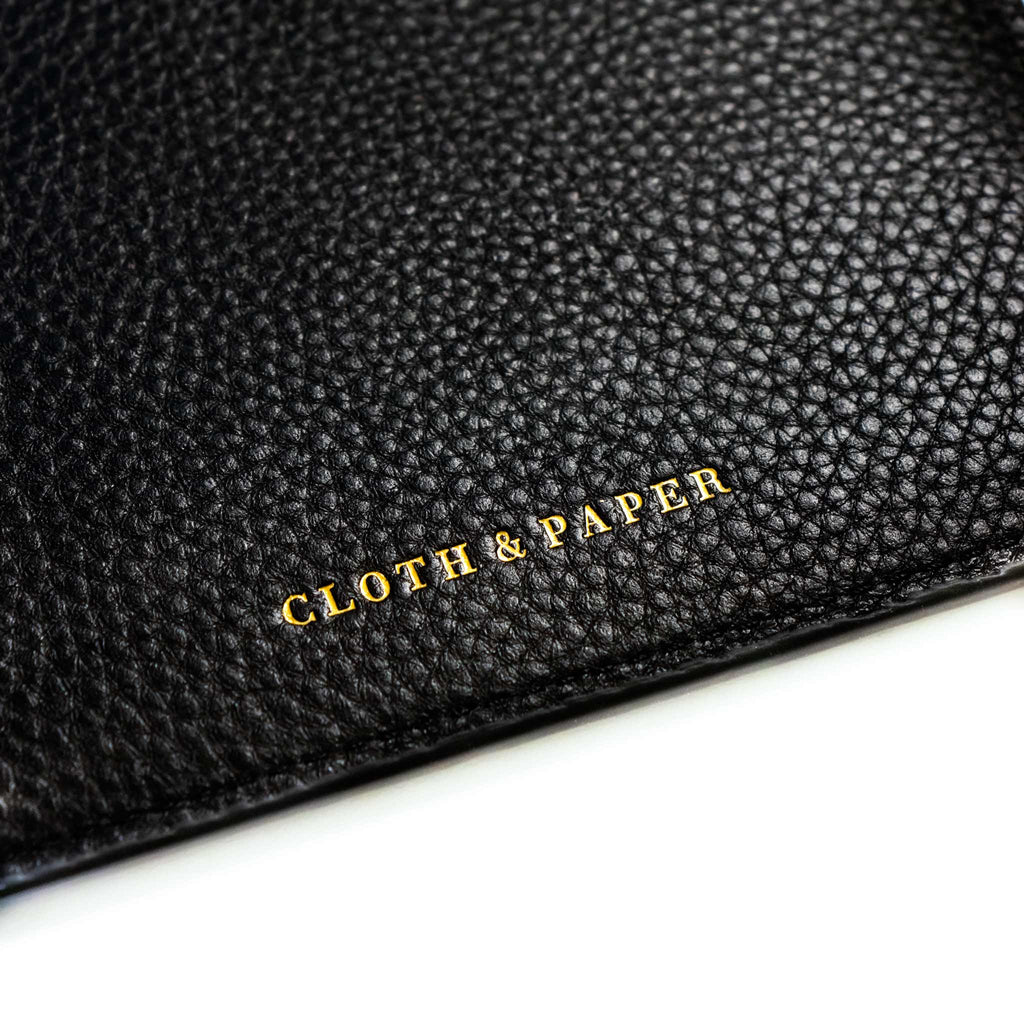 Close up on the Cloth and Paper logo stamped in gold on the inside of the back cover of a black agenda cover.