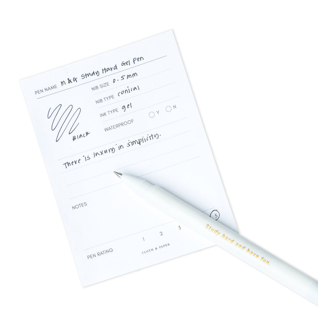 Black pen resting on a pen test sheet displaying a writing sample that details the pen's specs.