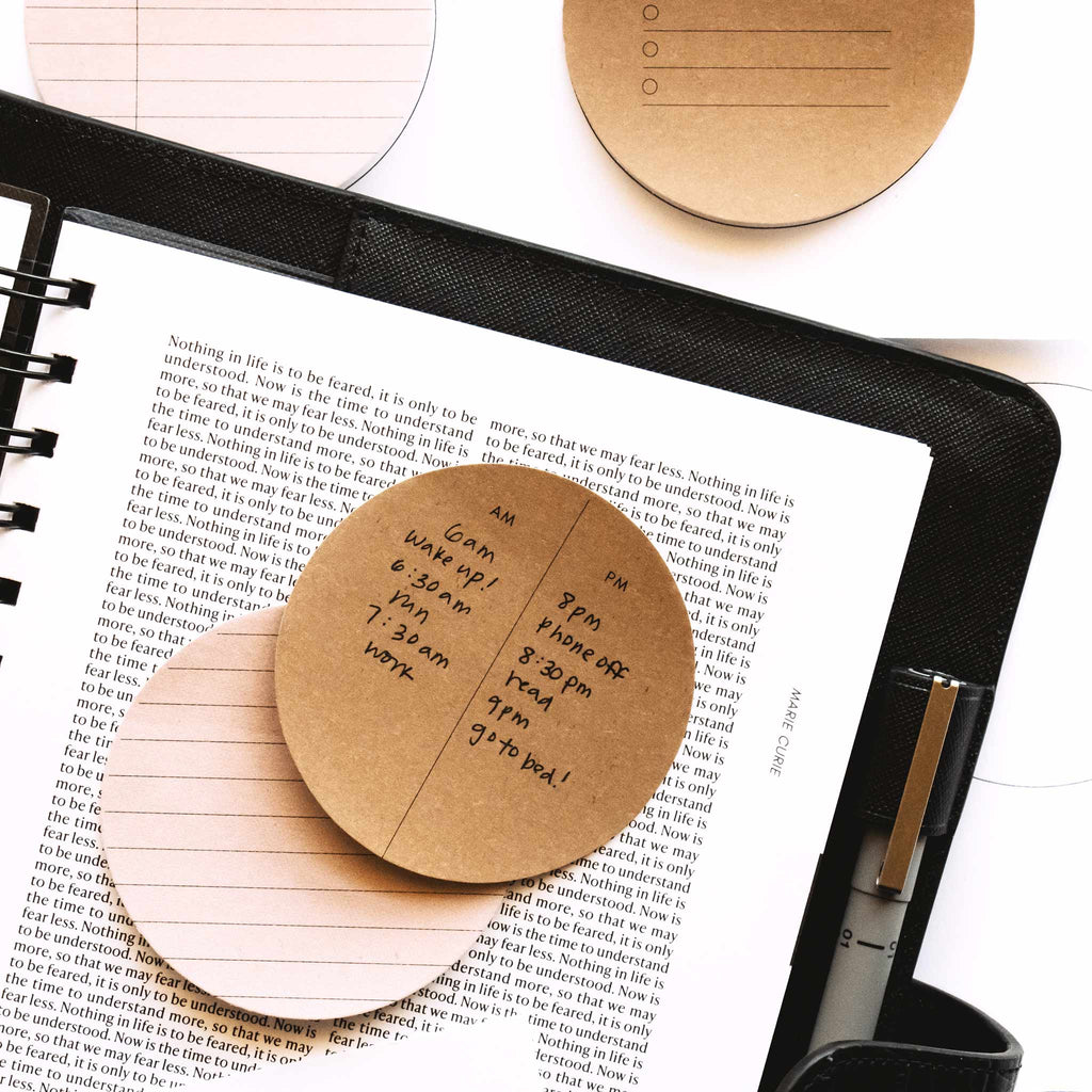 Printed circle sticky notes in use inside a leather planner cover with Uni Pin in planner's pen loop.