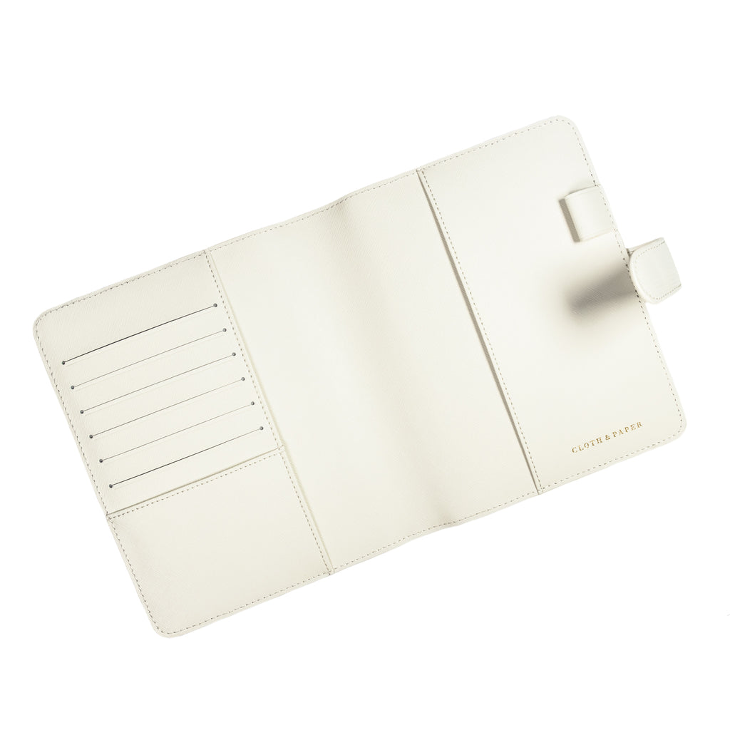 White agenda cover opened to show the inside. The pen loop, document pockets, passport pocket, and credit card slots are visible.