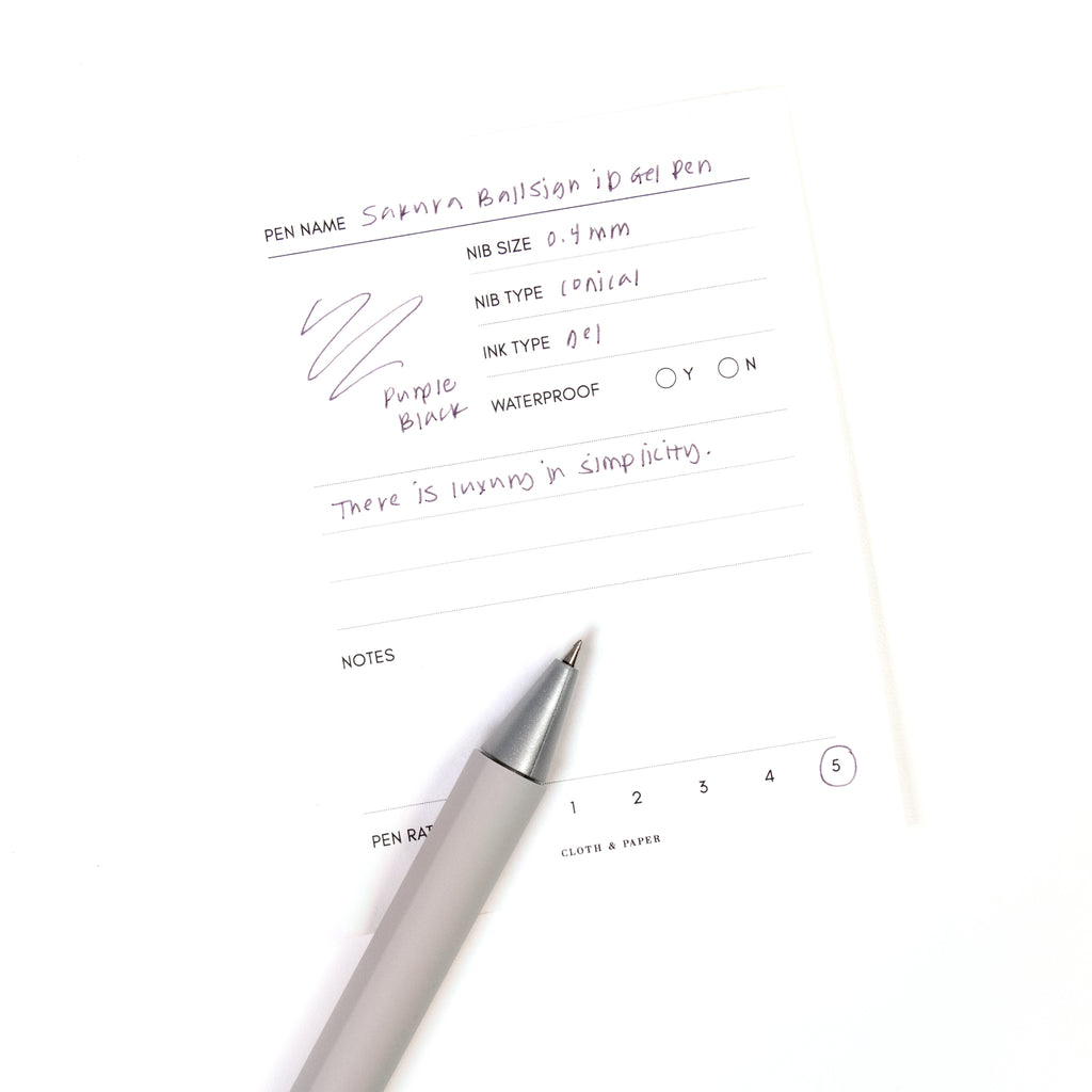Sakura Ballsign iD Gel Pen, 0.4 mm, Cloth and Paper. Purple black pen resting on pen test sheet displaying writing sample.