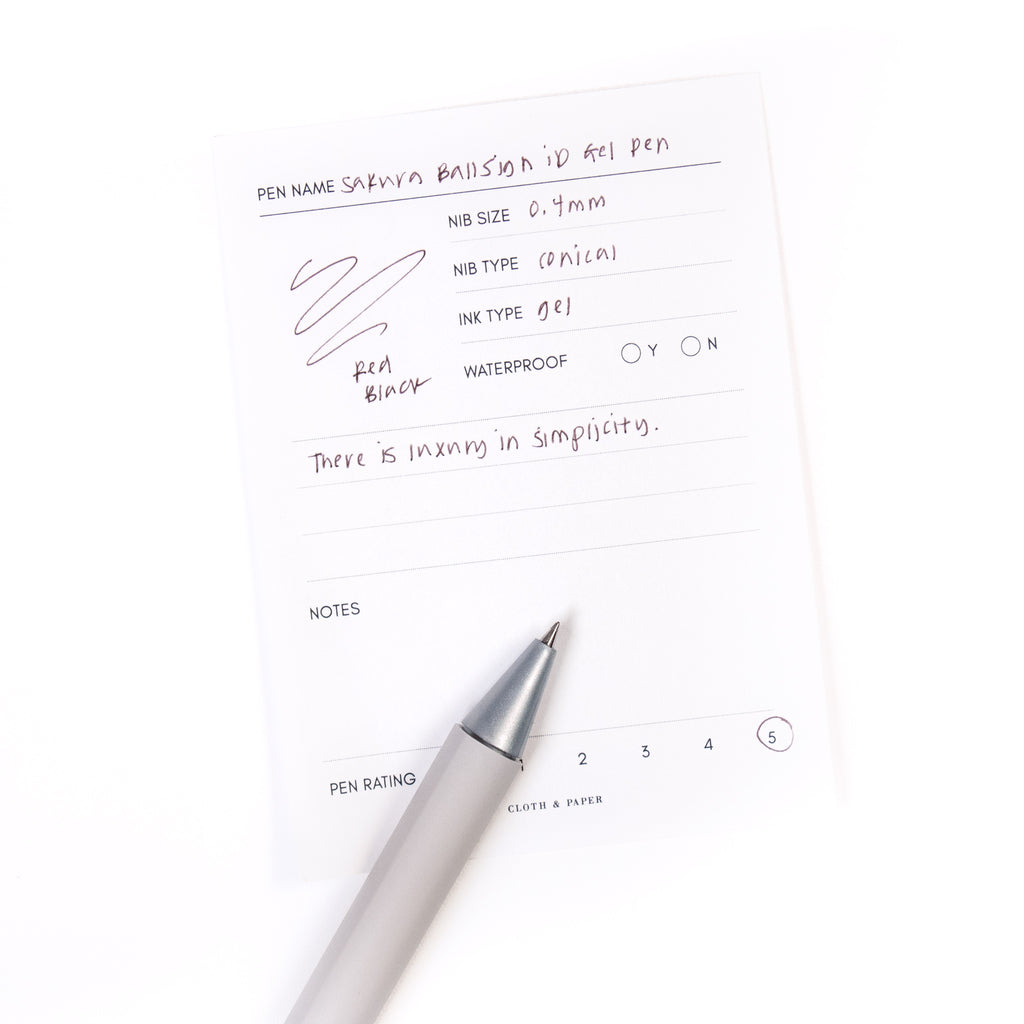 Sakura Ballsign iD Gel Pen, 0.4 mm, Cloth and Paper. Red black pen resting on pen test sheet displaying writing sample.