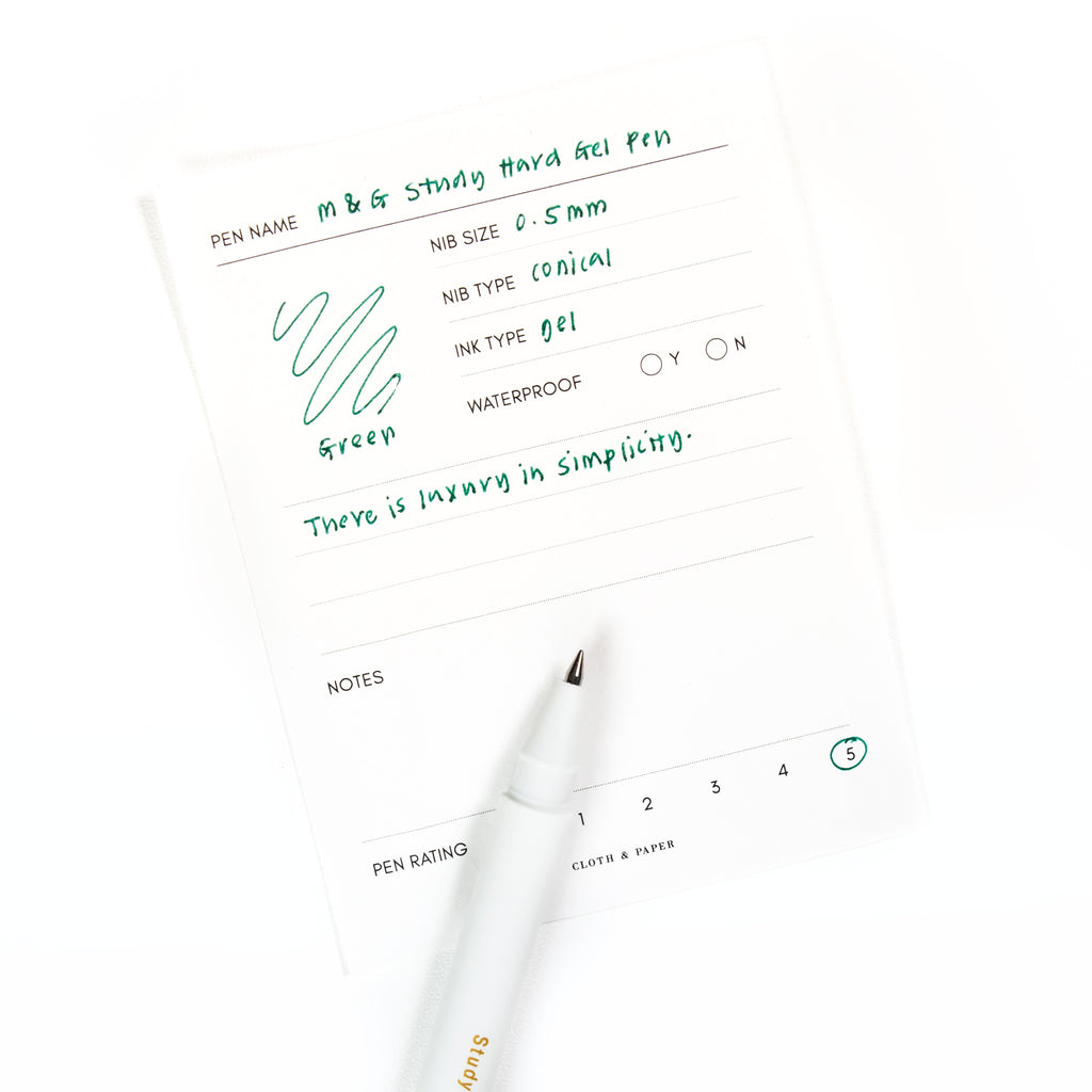 Green pen resting on a pen test sheet displaying a writing sample detailing the pen's specs.