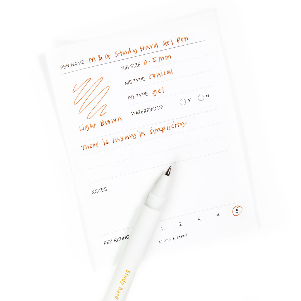 Light Brown pen resting on a pen test sheet displaying a writing sample detailing the pen's specs.