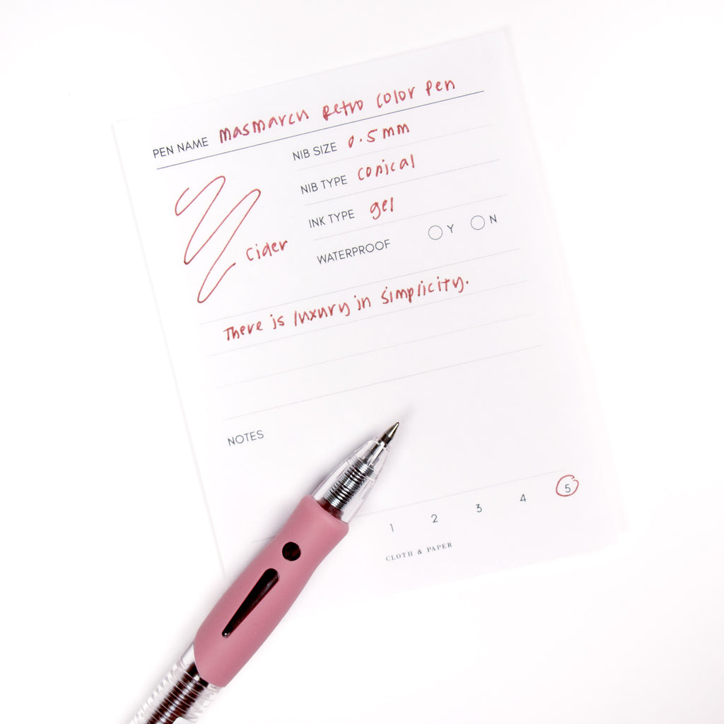 Cider pen resting on a pen test sheet displaying a writing sample detailing the pen's specs.
