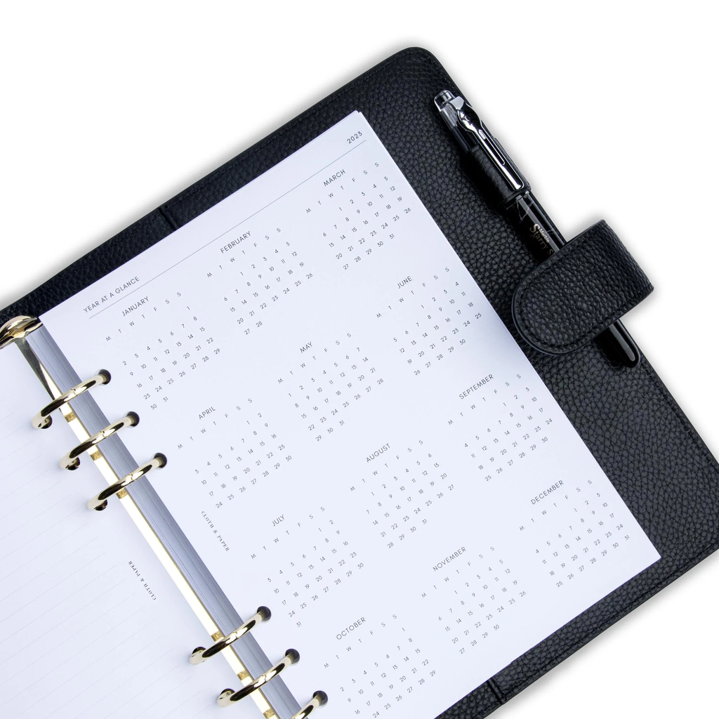 Close up of inserts in use inside a black leather agenda with silver rings. A black pen is inside the agenda's pen loop.